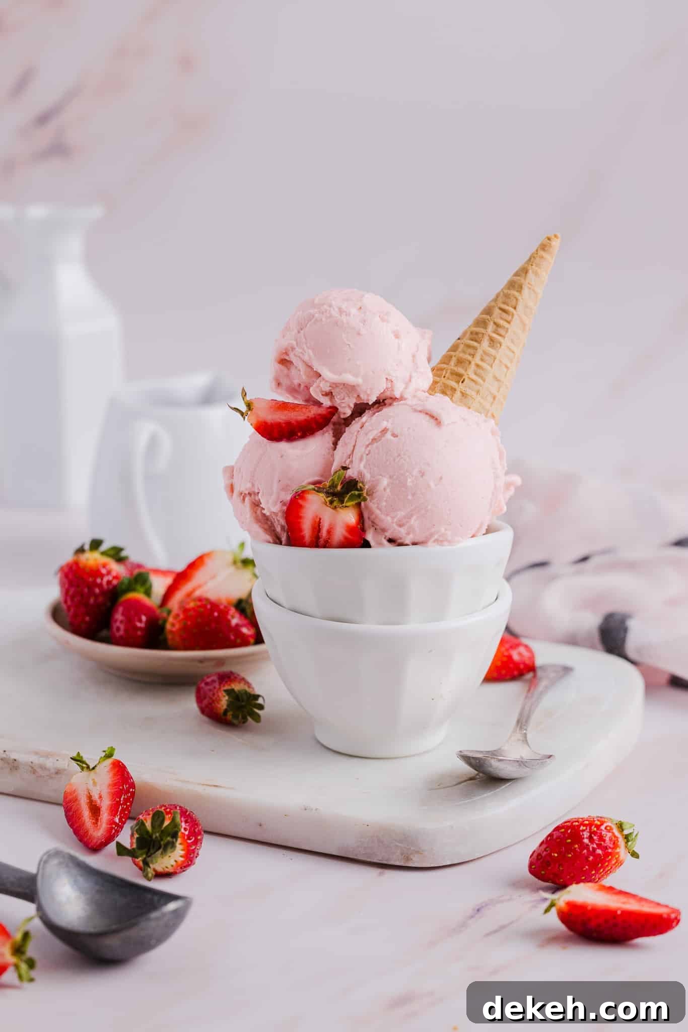 Side view of scoops of strawberry ice cream in a bowl with a sugar cone.