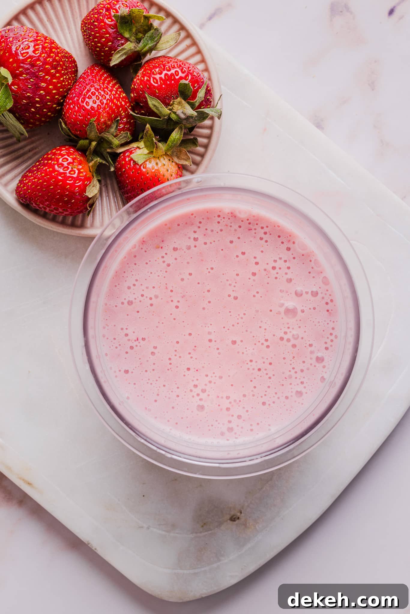 Ingredients for strawberry ice cream blended together in a Ninja Creami pint container.