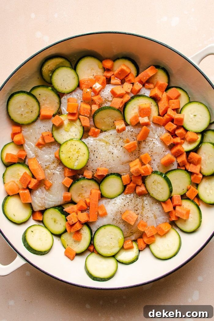 Phot shows diced zucchini and carrots sprinkled around the fish fillets