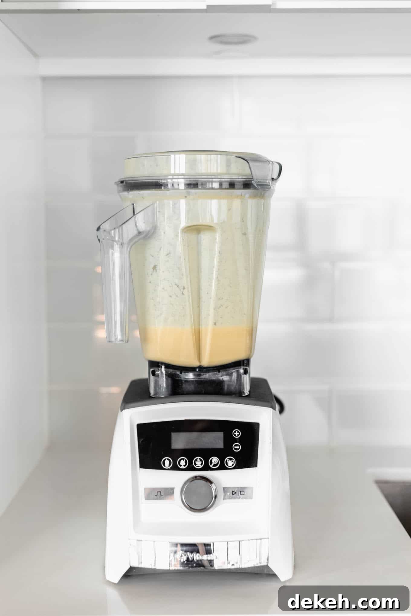 A white blender with orange smoothie in it