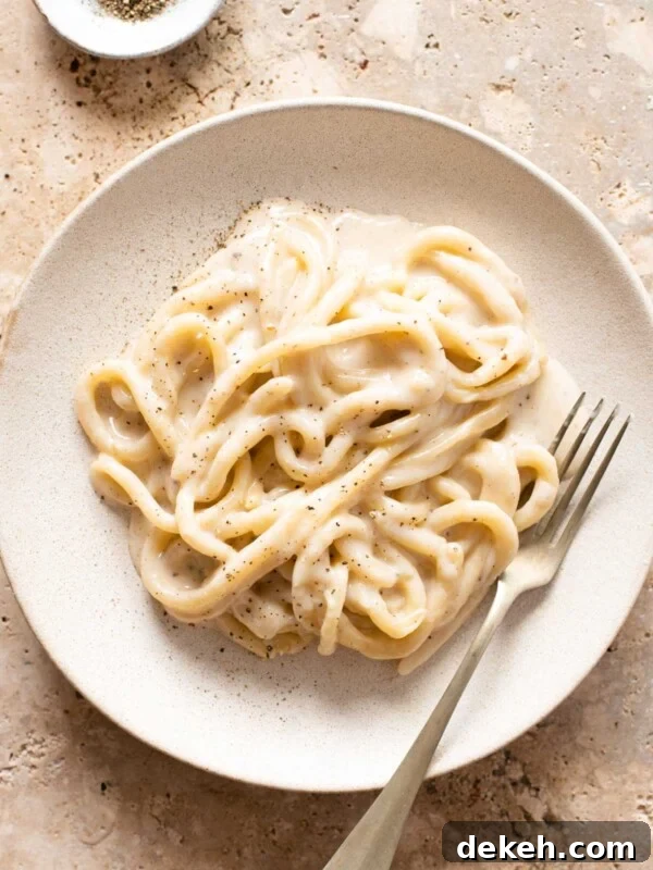 An overhead shot of pici pasta with cacio e pepe sauce on a plate