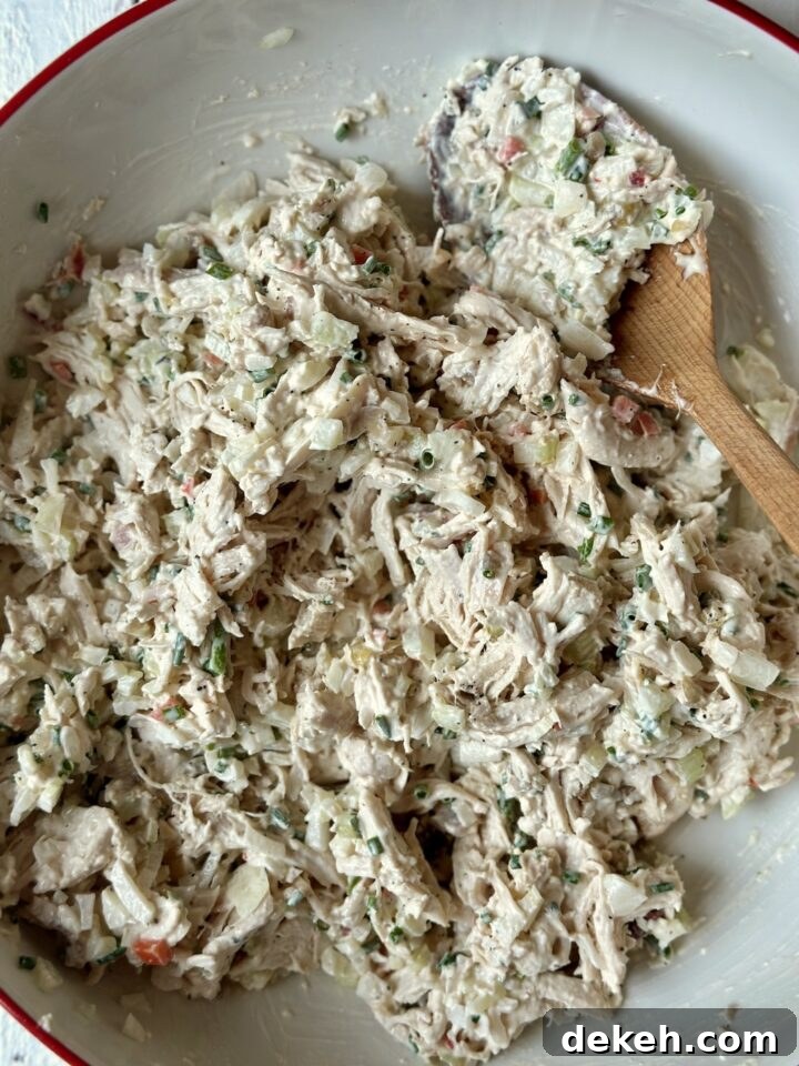 Chicken salad in a white mixing bowl with a red rim