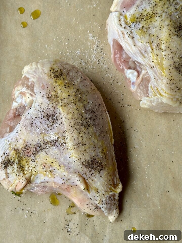 chicken breasts with olive oil, salt, and pepper on parchment paper