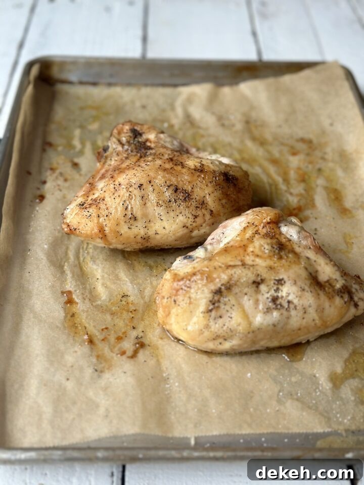 golden roast chicken out of the oven on a baking sheet with parchment paper