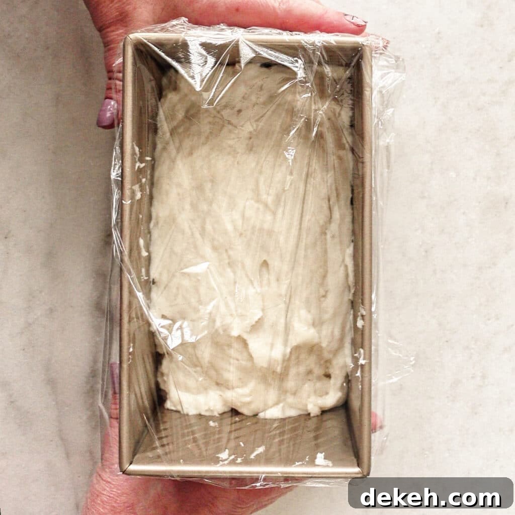 covering dough in gold loaf pan with plastic wrap.