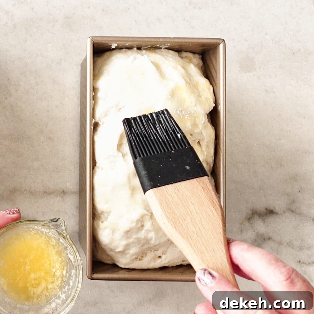 brushing melted butter onto risen dough.