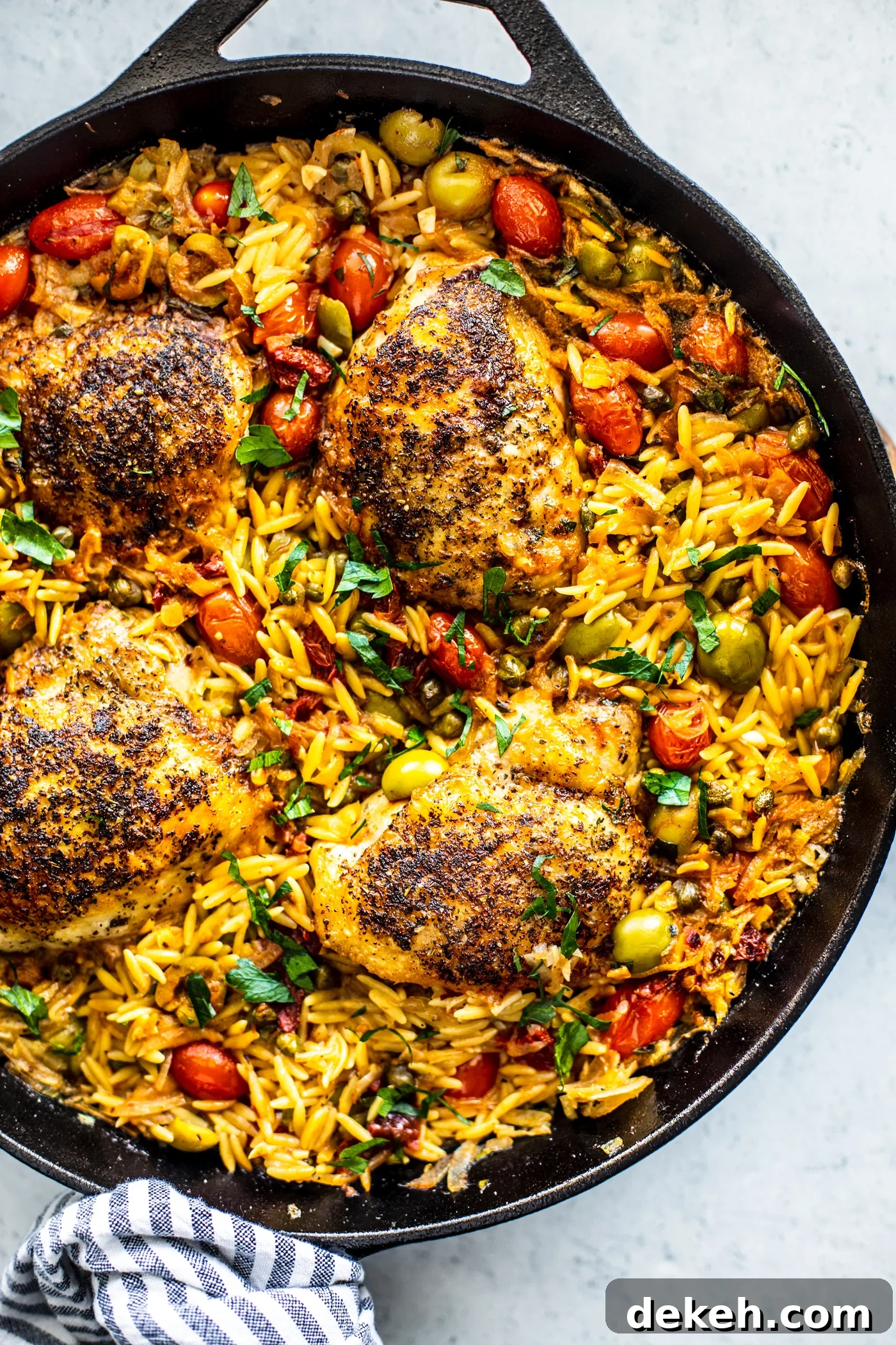 Overhead shot of skillet with orzo, crispy chicken, and veggies.