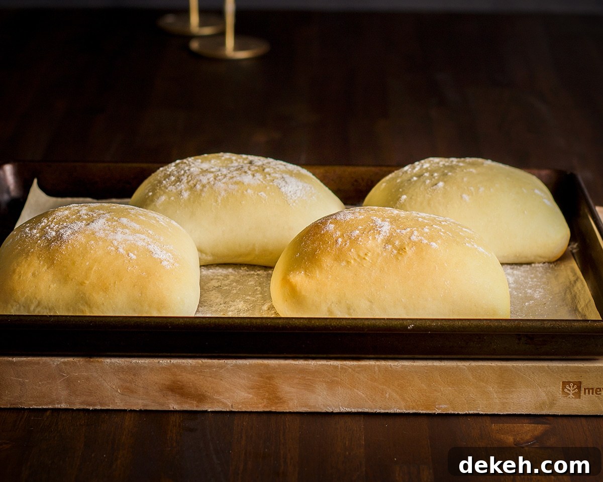Four freshly baked krautburgers on a baking sheet.