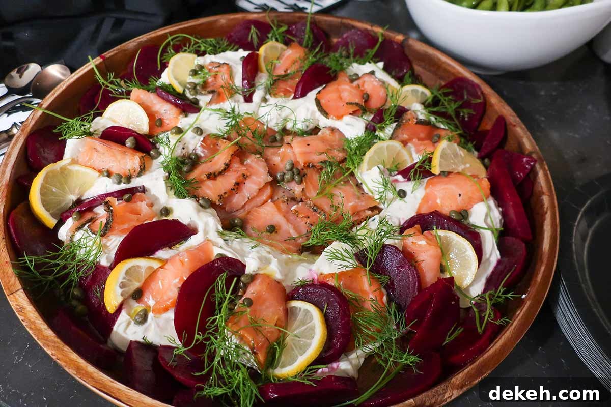 Scandinavian-style smoked salmon dip topped with roasted beets, fresh dill, and lemon slices on a serving platter — a colorful gluten-free appetizer.