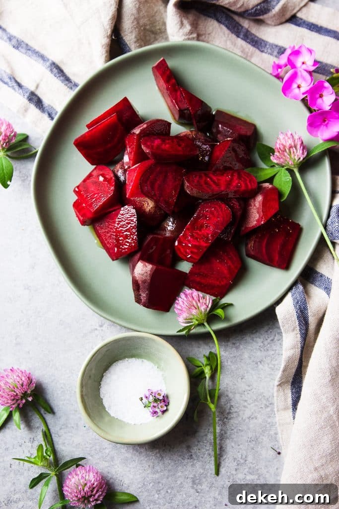Roasted beets on a plate. Fresh flowers on the table and a tablecloth. A pinch bowl with sea salt.