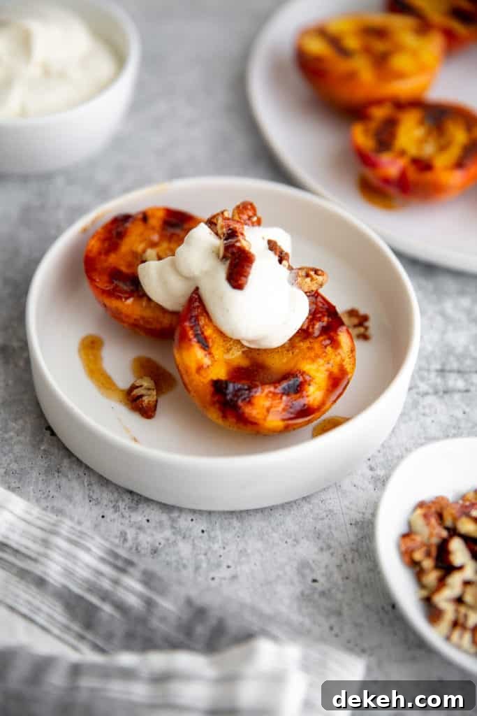 Grilled peaches in a bowl topped with whipped cream and pecans. 