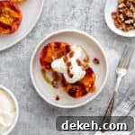 Grilled peaches on a plate topped with cardamom whipped cream and toasted nuts.