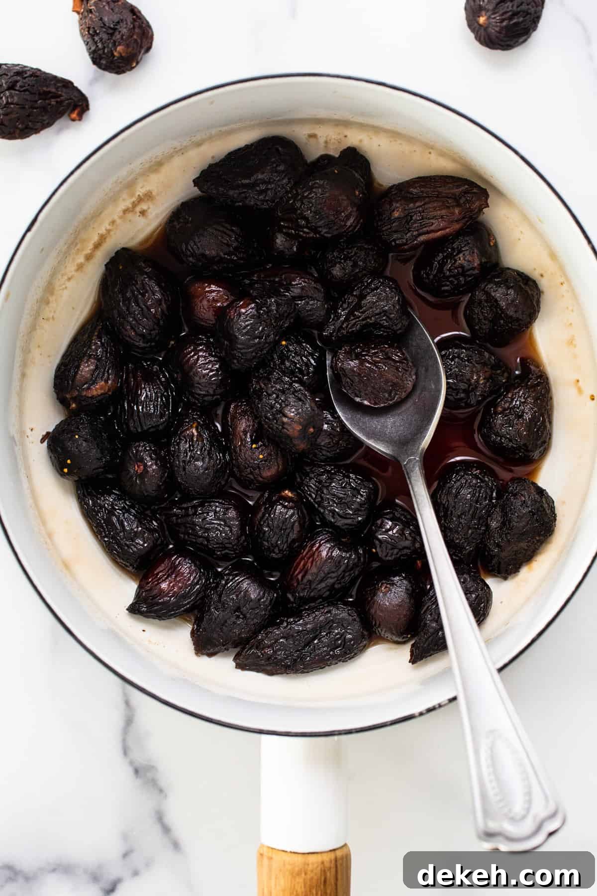 Dried figs in a pan with a spoon.