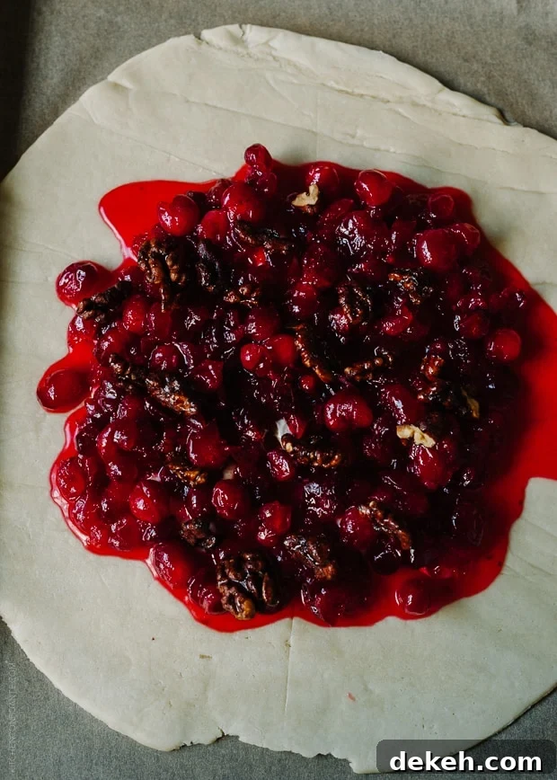 Spreading cranberry filling over a large piece of galette dough.