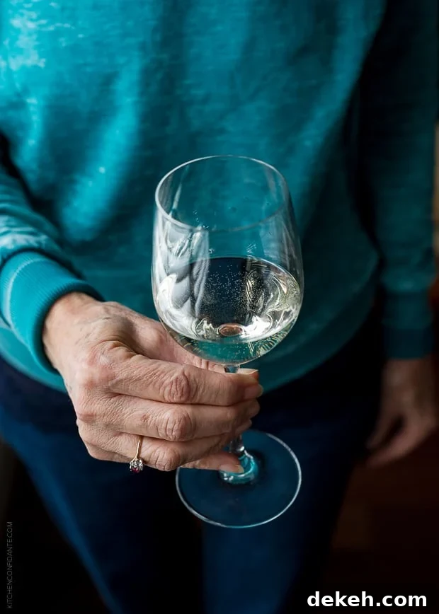 Woman in a blue sweater holding a glass of wine.