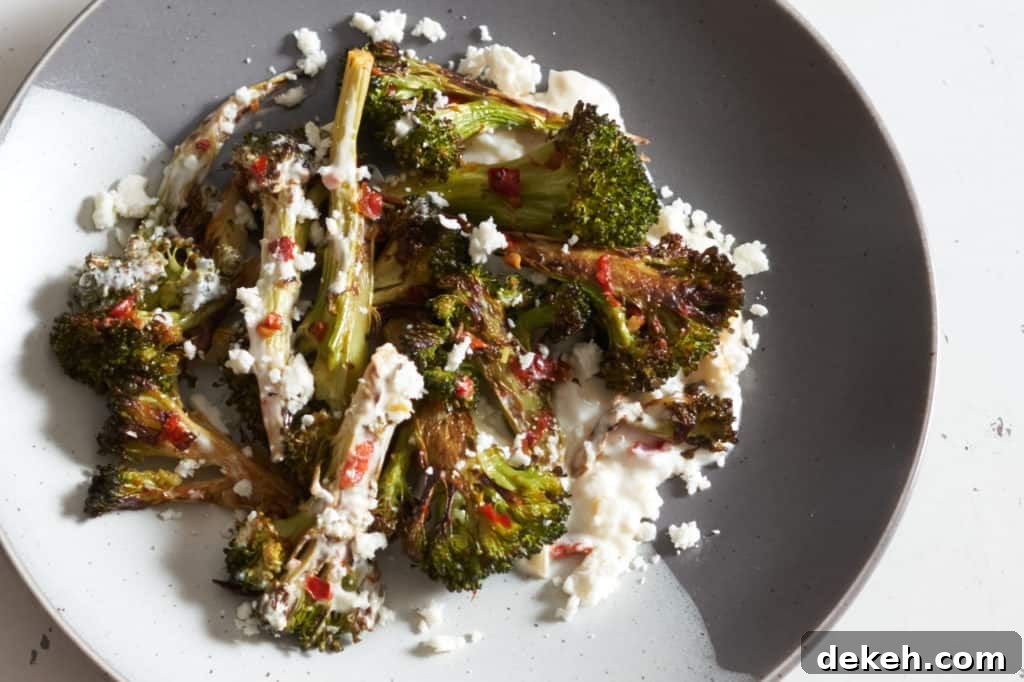 Charred broccoli with Calabrian chili paste on a grey and white plate.