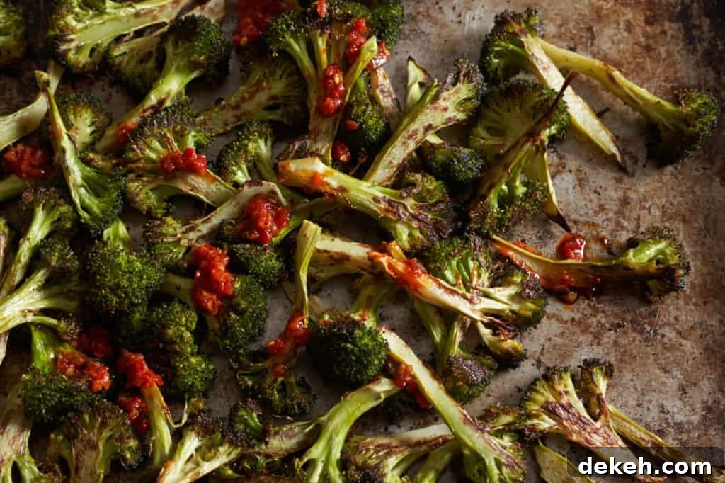 Charred broccoli on a sheet pan drizzled with Calabrian chili paste.