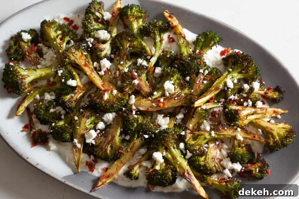 Charred broccoli with calabrian chili, feta, and lemon yogurt sauce on a gray and white plate.