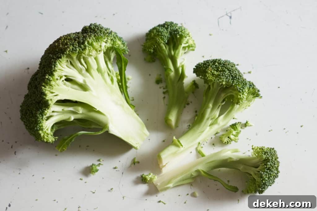 A crown of broccoli next to three broccoli florets.