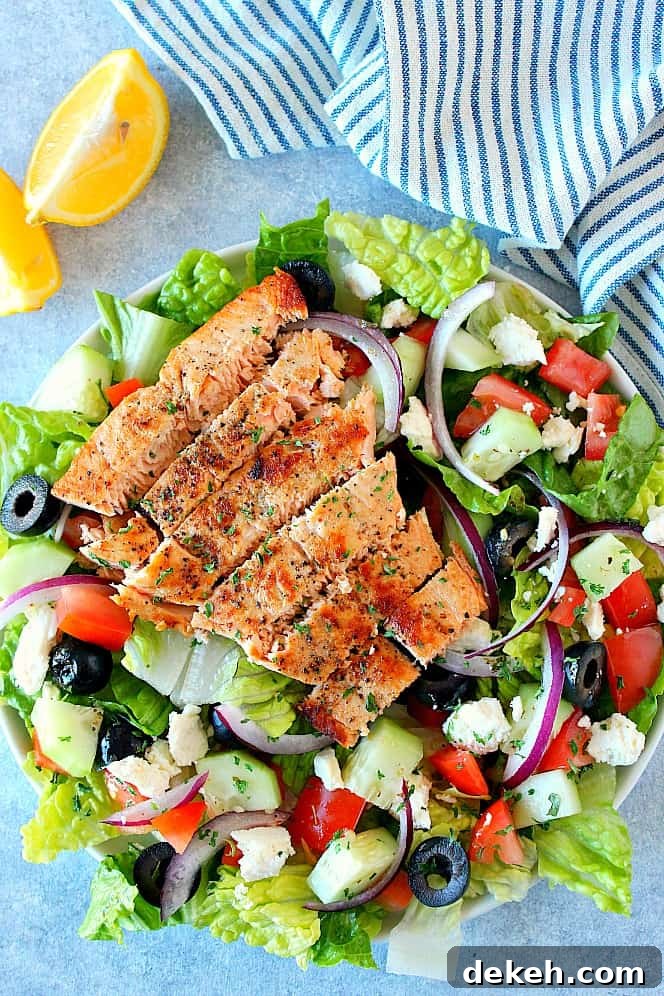 Overhead shot of Greek salad with sliced salmon on top, on plate.