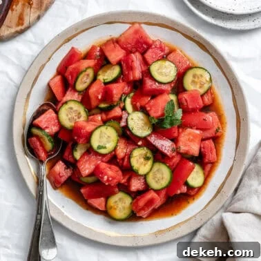 a dressed Watermelon Tomato Salad on a white plate with a spoon on the side.