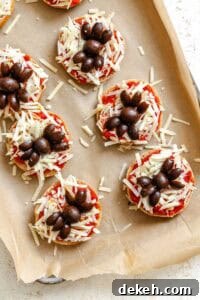 Process shot showing pre baked Mini Spider Pizza [Bagel Bites] on baking tray.