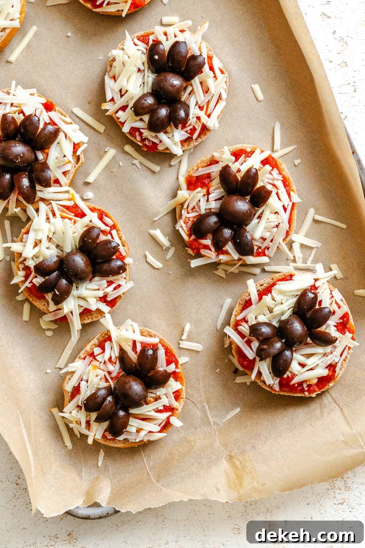 Process shot showing pre baked Mini Spider Pizza [Bagel Bites] on baking tray.