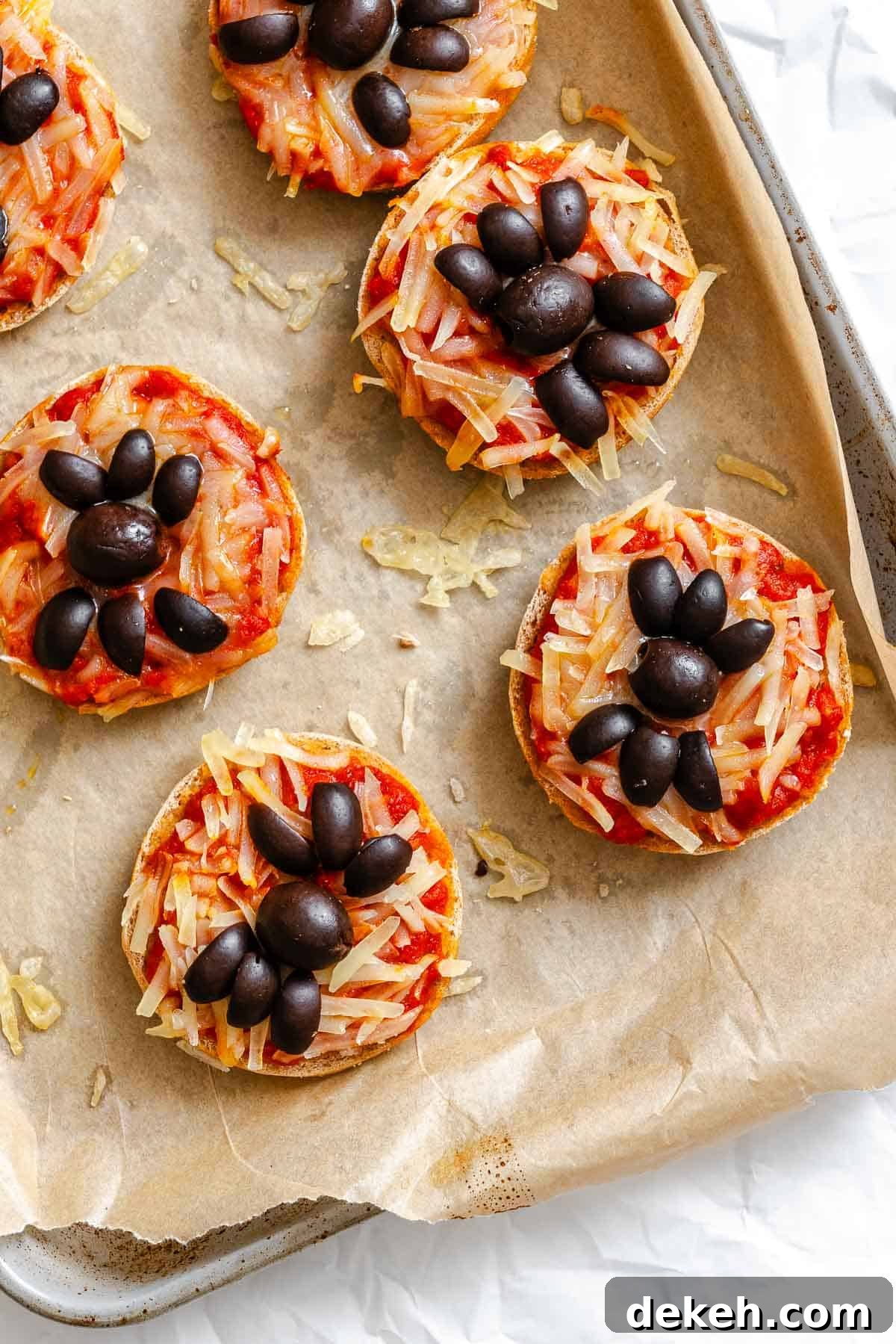 Process shot showing post baked Mini Spider Pizza [Bagel Bites] on baking tray.