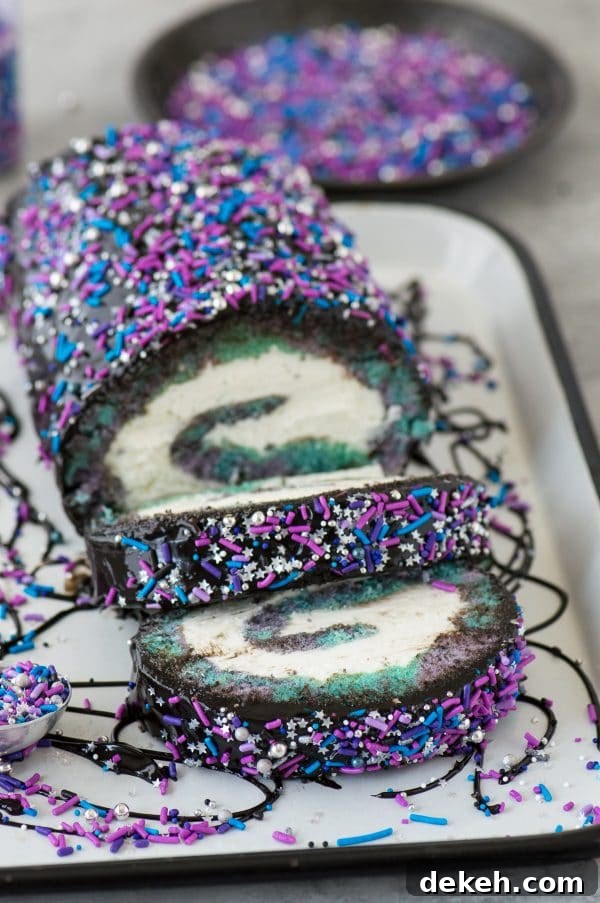 Multi-colored galaxy cake roll with black chocolate ganache, topped with sprinkles!