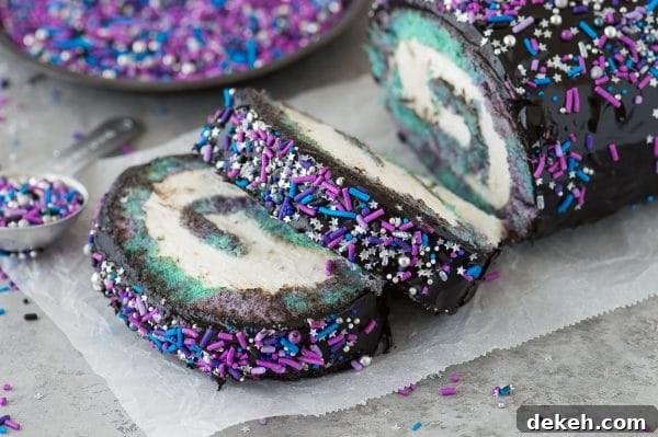 Multi-colored galaxy cake roll with black chocolate ganache, topped with sprinkles!