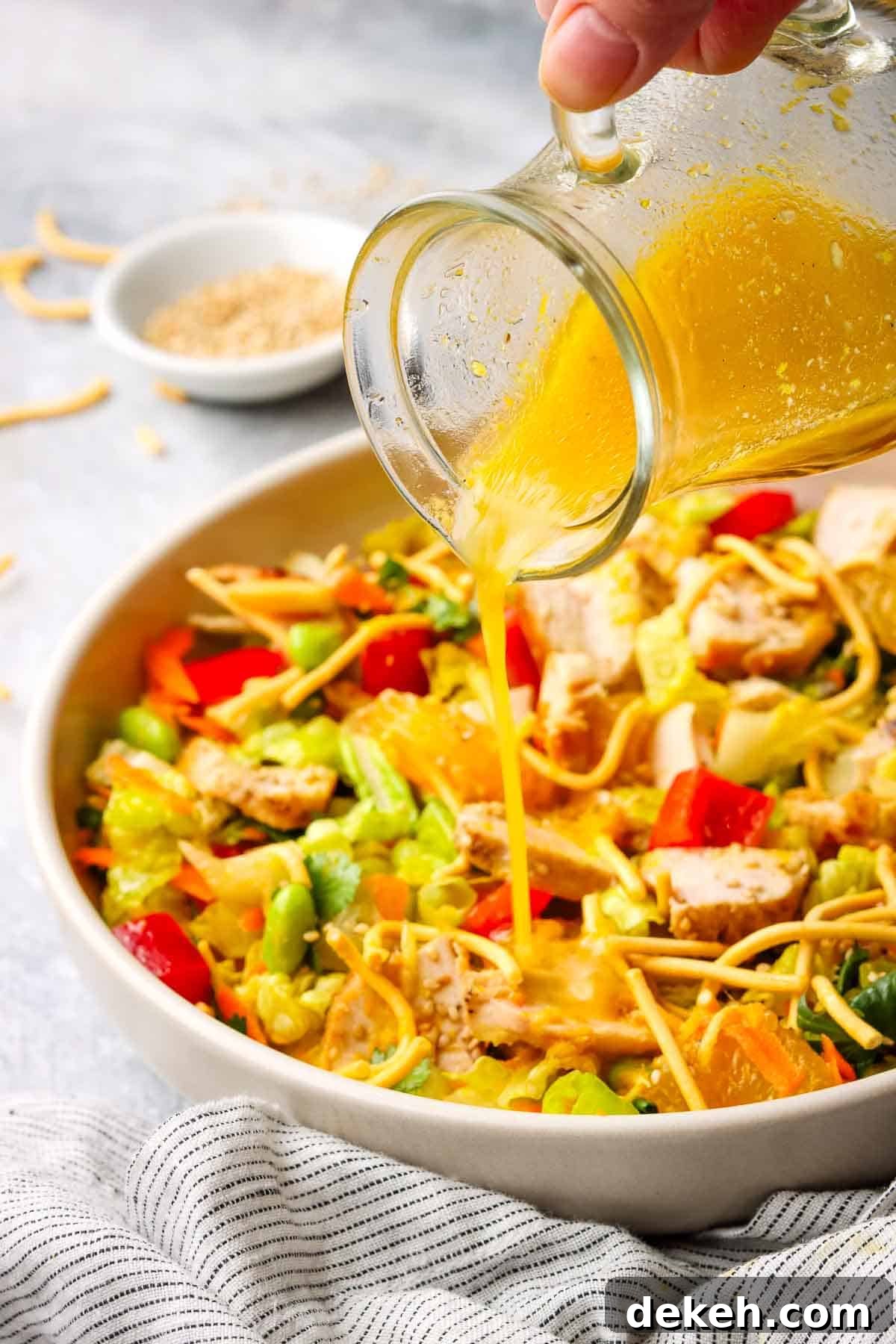 pouring orange ginger dressing on a salad