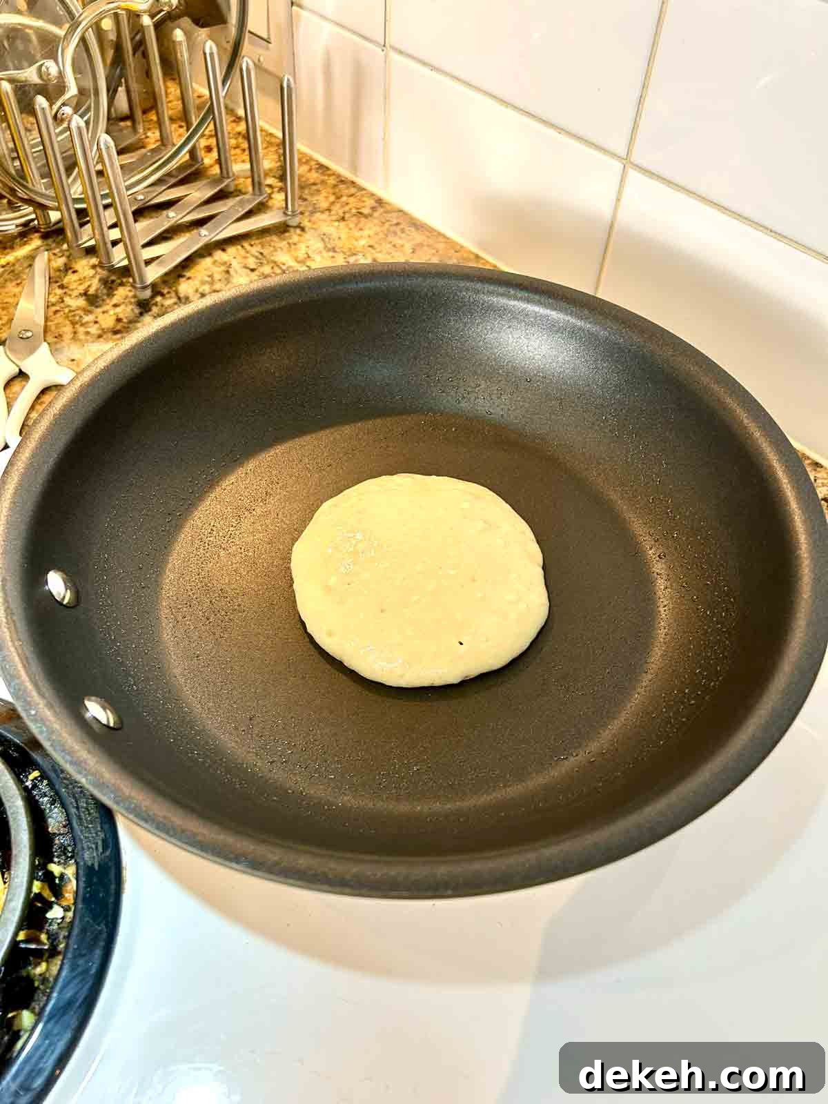 first side of pancake being cooked in nonstick pan.