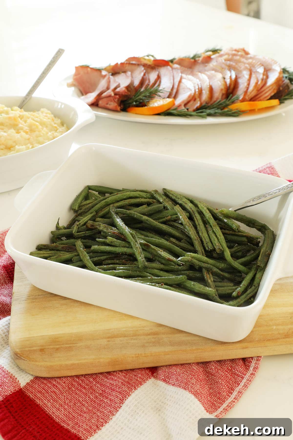 Baked Green Beans on a wooden cutting board in a white serving dish.