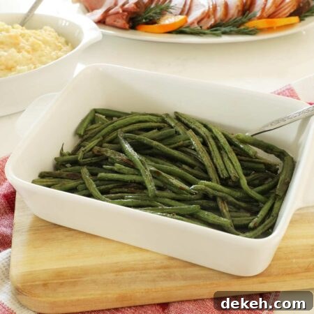 Baked Green Beans in a white serving dish on a wooden cutting board.