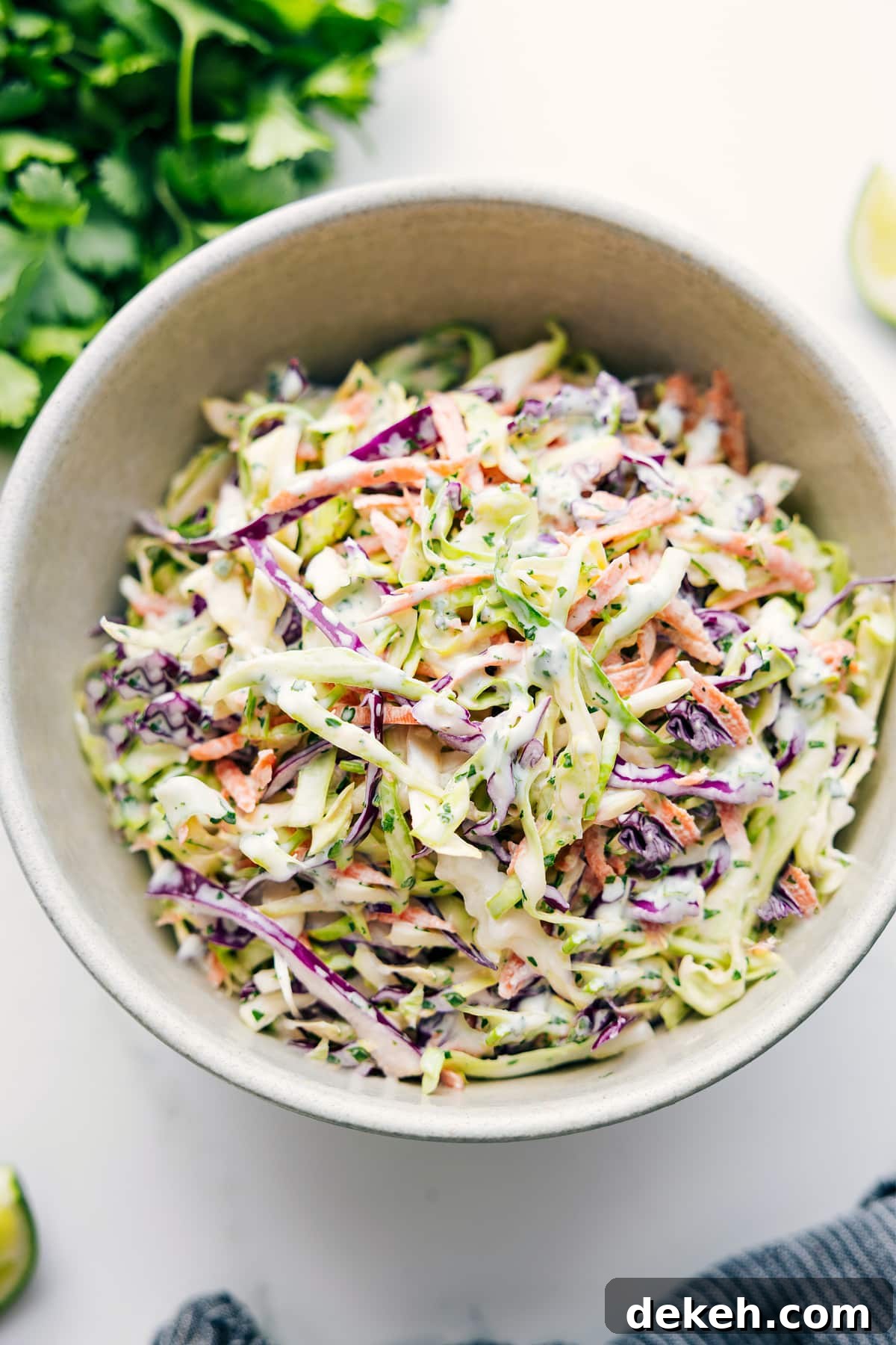 Mexican slaw tossed together in a bowl with dressing evenly coating the cabbage.