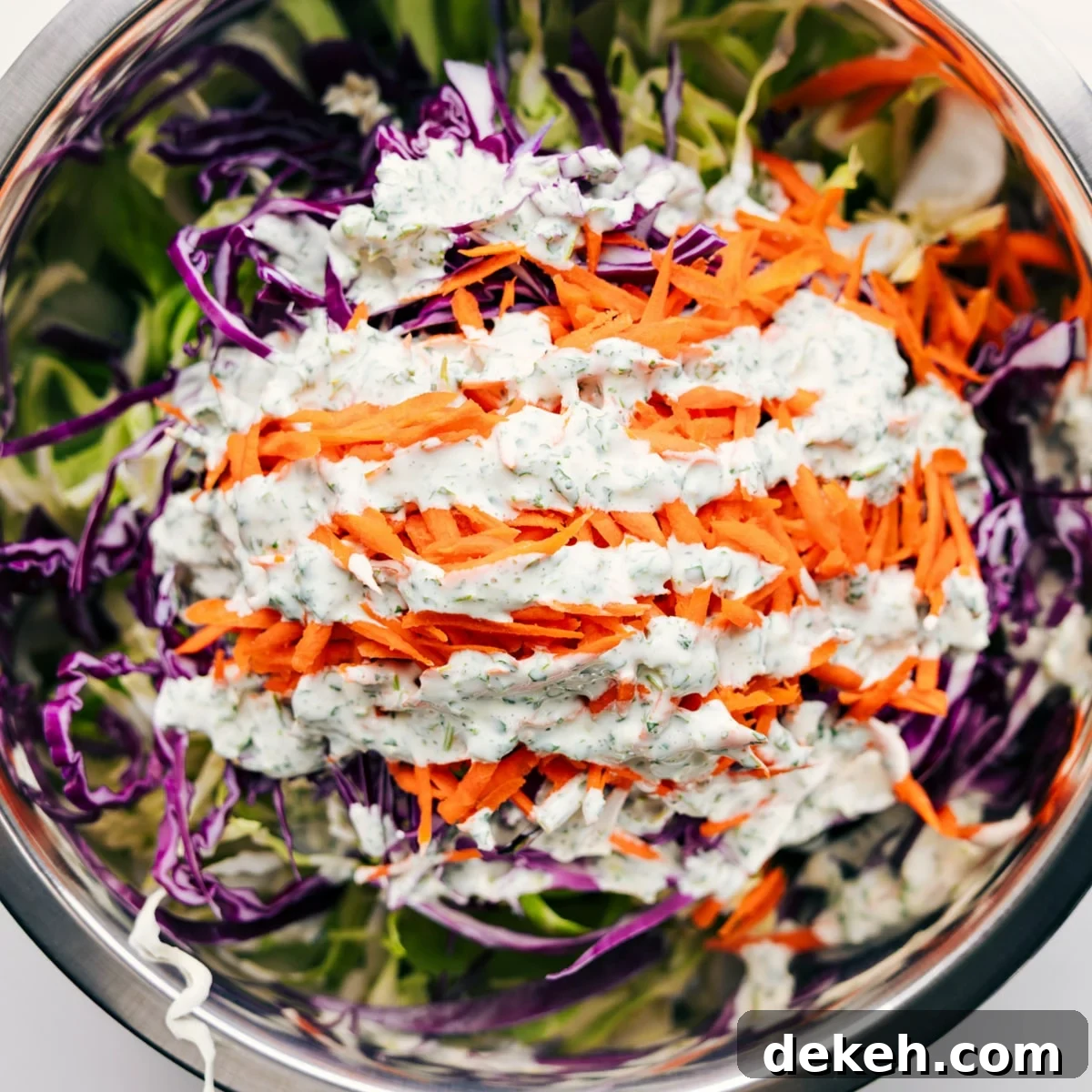 All the ingredients added to a large bowl with the dressing drizzled on top.
