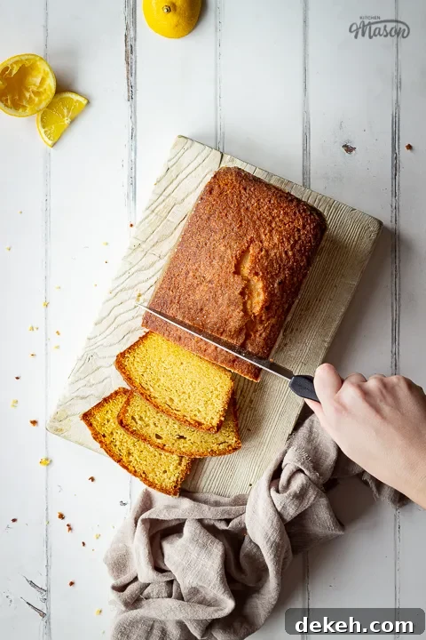 A top down view of someone slicing a moist lemon drizzle cake