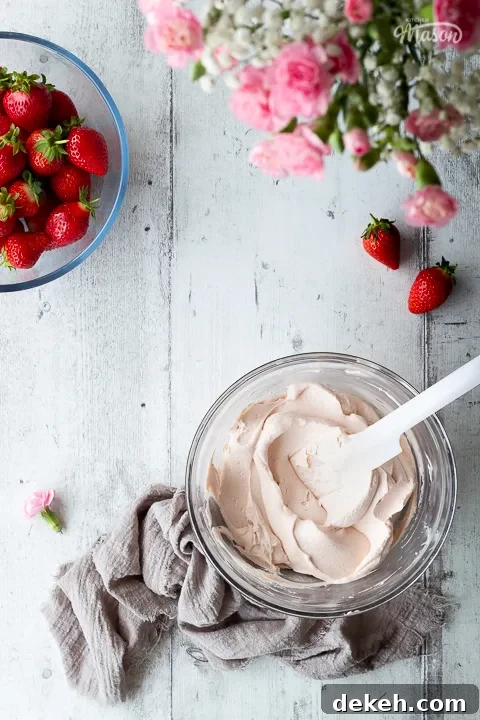A bowl of strawberry frosting with some flowers