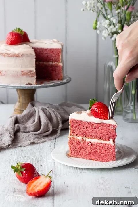 Someone pushing a fork into a slice of strawberry cake