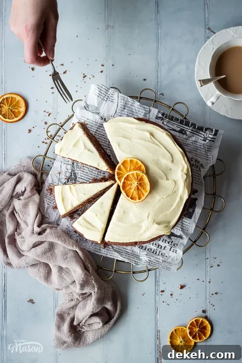 A hand reaching in with a small fork to a sliced chocolate cake