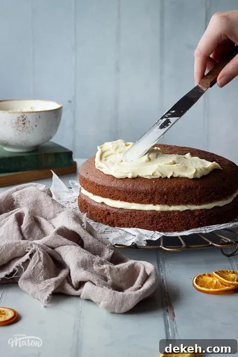 Front view of white chocolate filling being spread on a chocolate orange cake