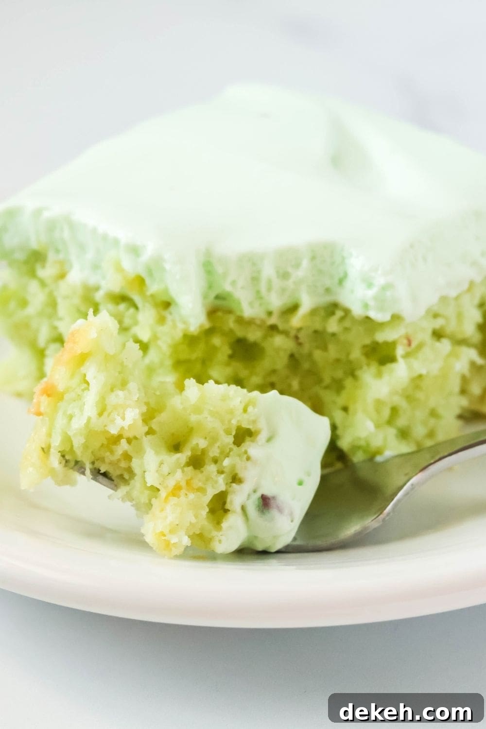 close-up view of a fork holding a bite of cake mix pistachio pineapple cake.