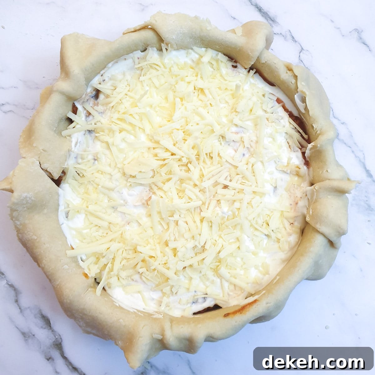 Sour cream and grated cheese on top of the meat filling in a pie dish.