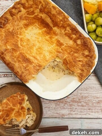 An overhead shot of granny's chicken pie with a slice removed and served on a plate next to the baking dish.