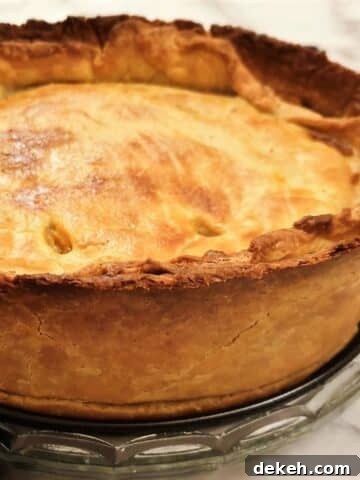 A side-on view of a baked beef and onion raised pie showing the depth of the pie.