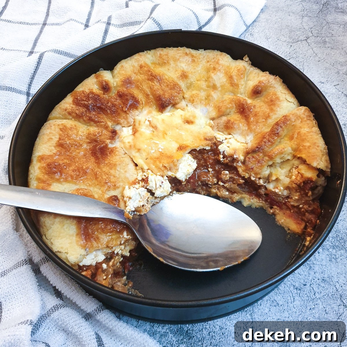 A tex mex beef pie in a baking dish with a slice removed to show the inside.