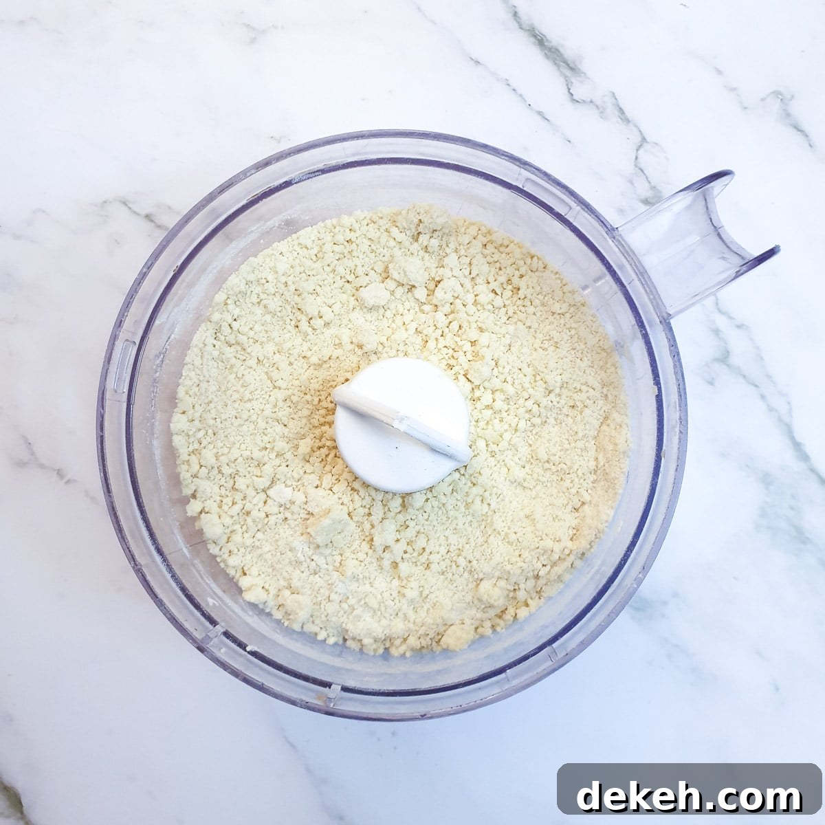Flour, cheese and butter in a food processor after having been pulsed to a breadcrumb consistency.