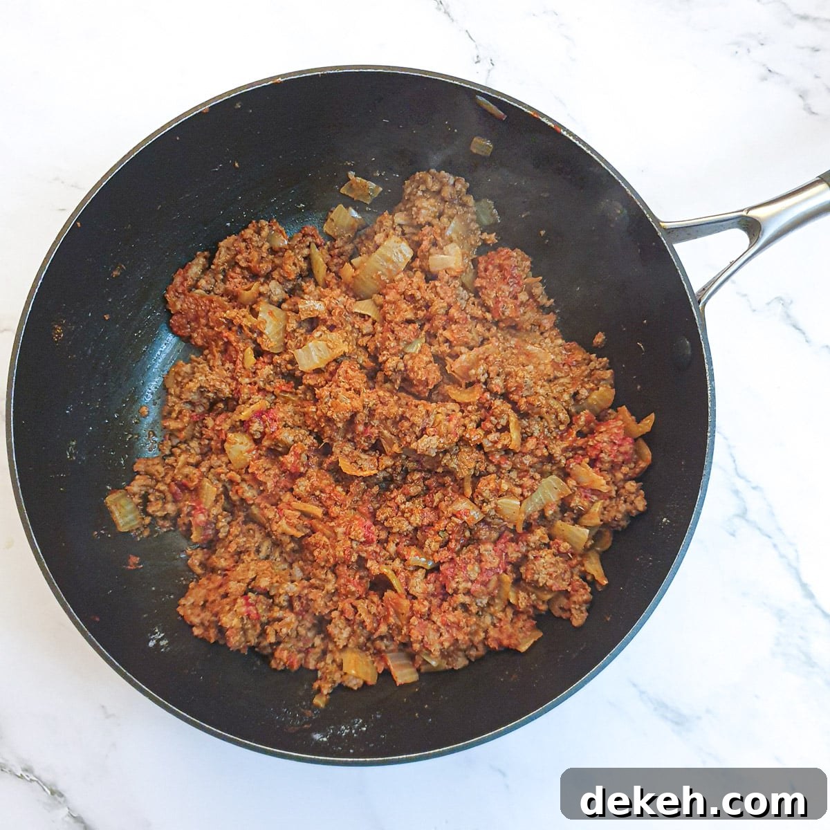 Ground beef in a pan after having been mixed with tomato paste, flour and fajita spices.