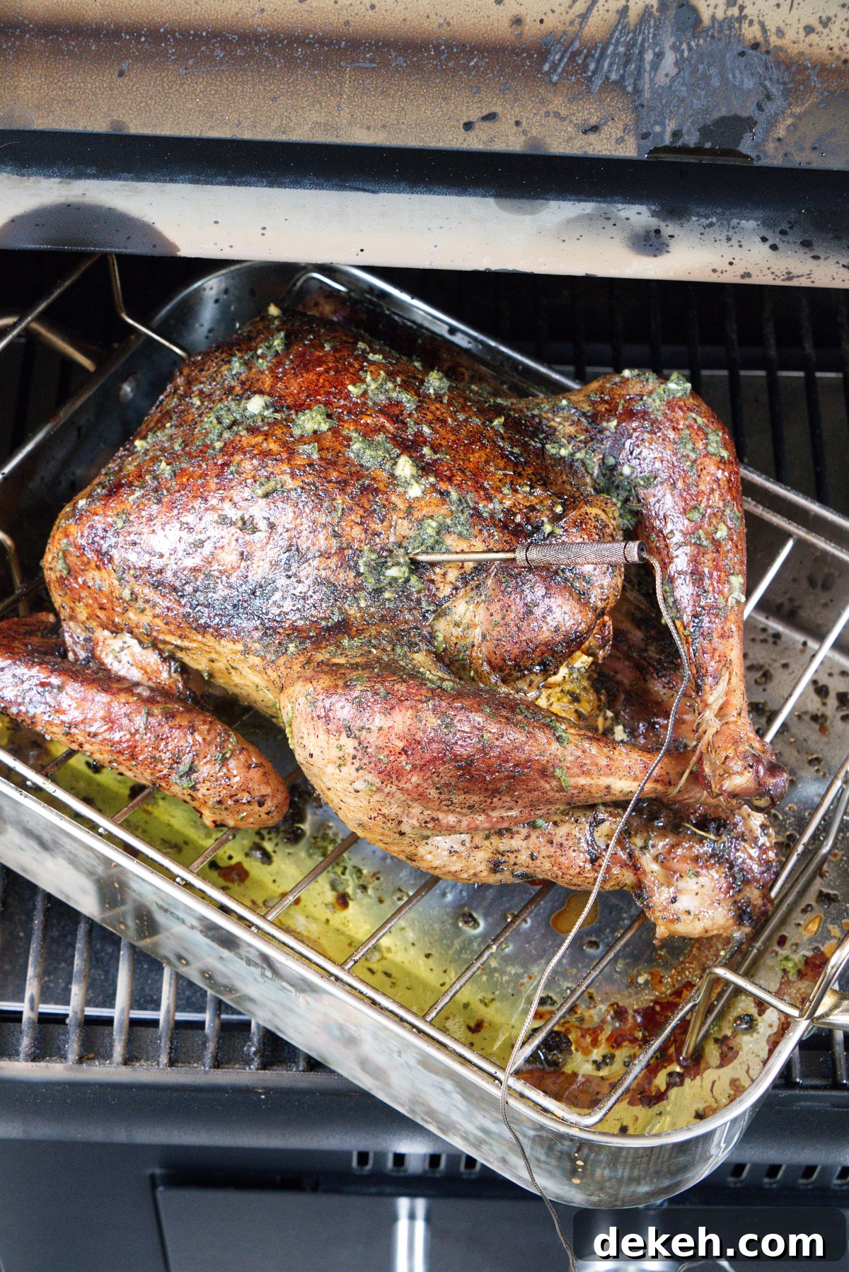 Dry brine smoked turkey on the Traeger grill, smoking in a roasting pan on the grill.