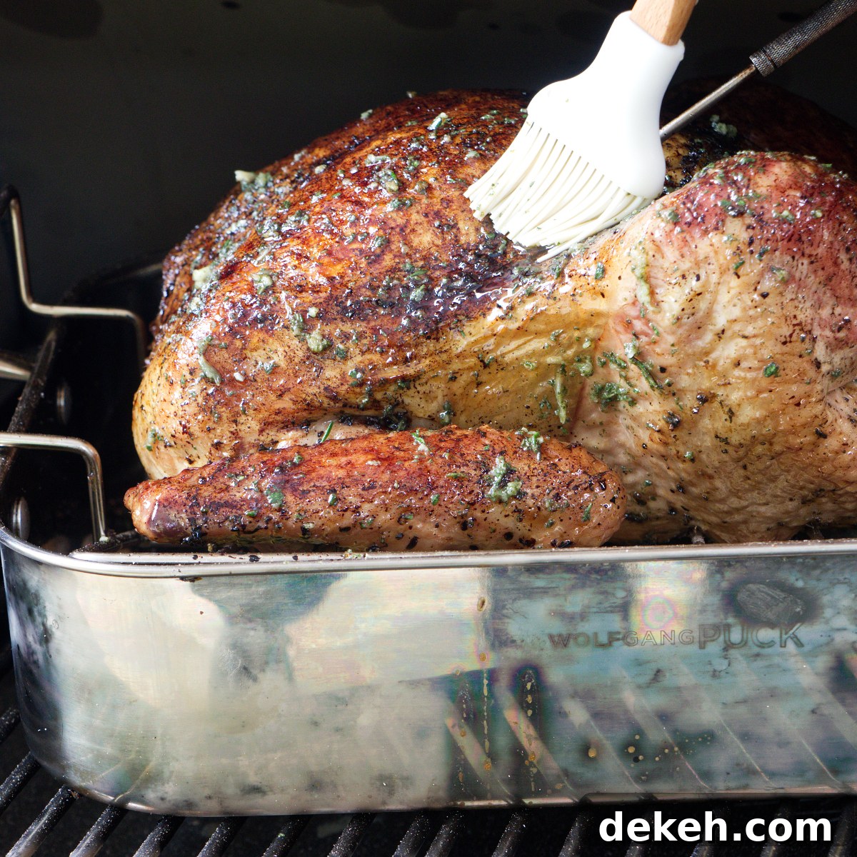 Basting the smoked turkey while it is on the pellet smoker grill.